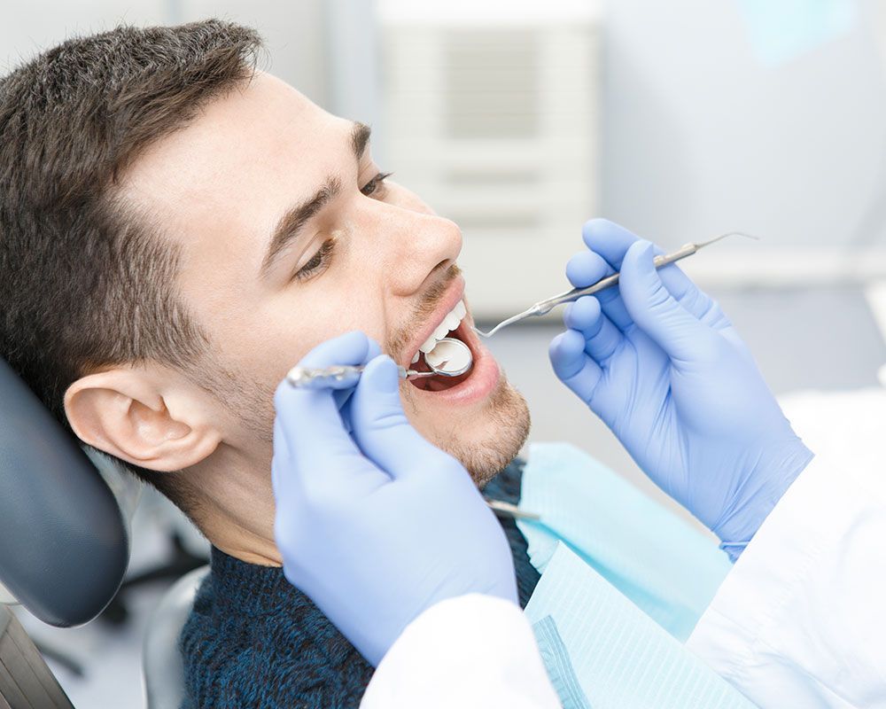 Patient wird bei zahnärztlicher Untersuchung mit Spiegel und Sonde behandelt