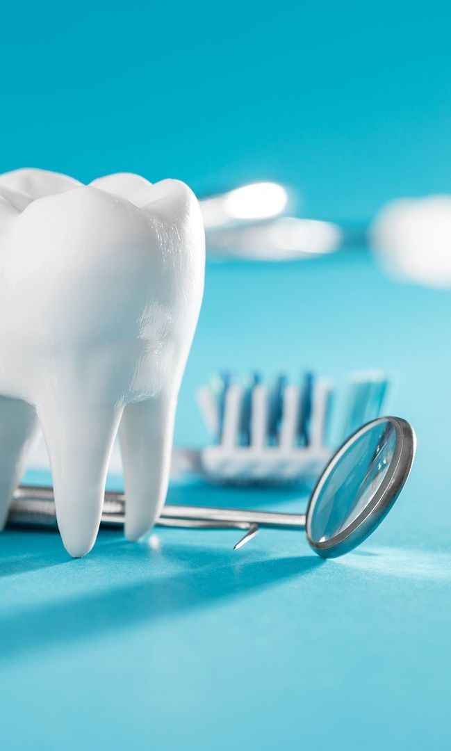 Modell eines Zahns mit Zahnarztspiegel und Zahnbürste auf blauem Hintergrund